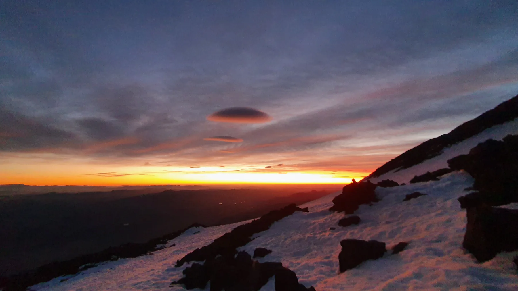 First light over the Argentine lake district from high on Lanín, snowfield in the foreground